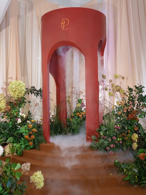 Monogrammed red archway ceremony installation surrounded by florals