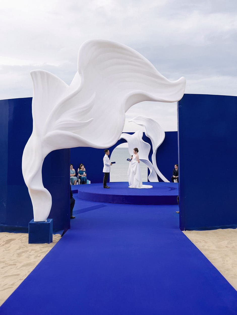 Blue-themed beachfront wedding ceremony with sculptural arch