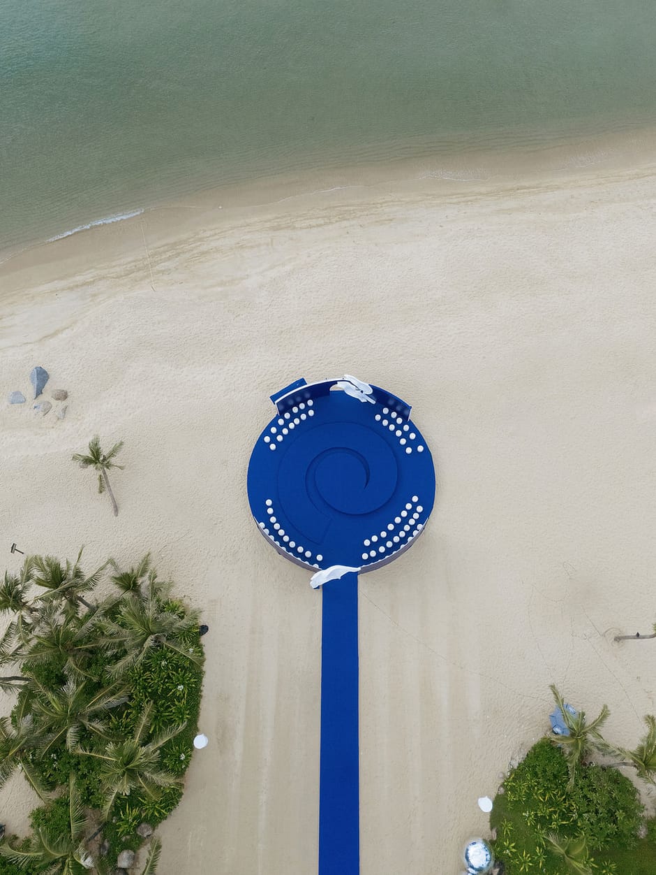 Aerial view of a blue beachfront wedding stage installation