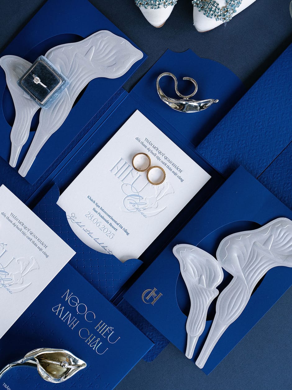 Flat lay of a navy and blush wedding invitation suite with engagement ring
