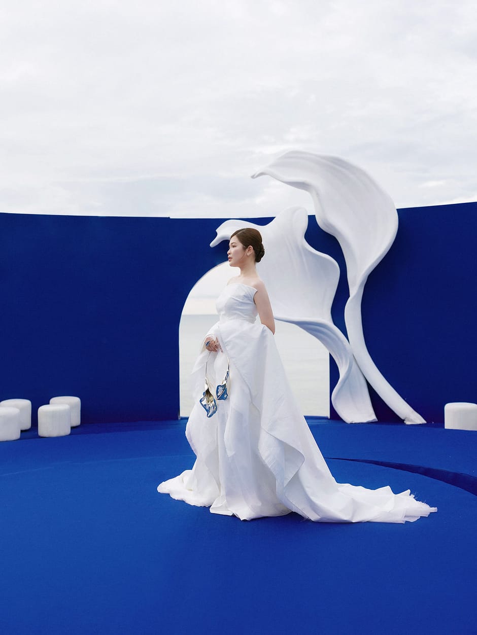 Bride in a white gown standing before a sculptural blue wedding backdrop